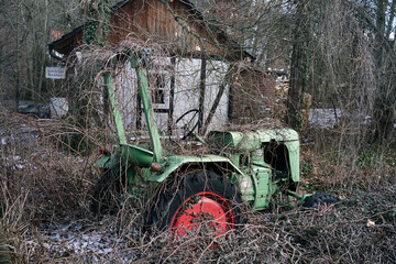 Ausrangierter Traktor, völlig von überwuchert von Strauchwerk, Ranken und Kletterpflanzen