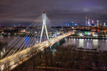 Swietokrzyski Bridge over the Vistula River with a panoramic view of the center of Warsaw at night....