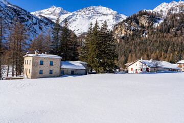 Sunny panorama of the imposing Swiss Alps with abundant snow in the foreground and stone cottages...