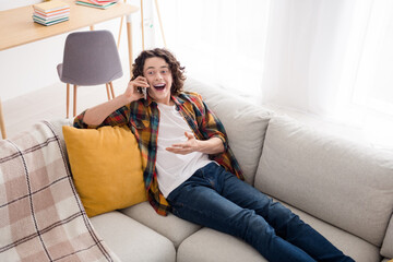 Obraz premium Photo of positive excited guy dressed checkered shirt talking modern device relaxing couch indoors house home room