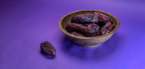 Raw date fruit ready to eat in bronze bowl on violet color background. Islamic religion and ramadan...