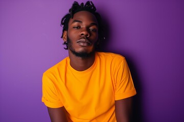 Fototapeta premium young black man wearing highlighter orange neon t shirt on a bold purple background