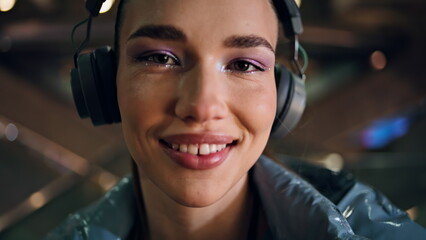 Closeup young woman face with bright makeup wearing wireless headphones. 