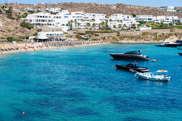 Psarou beach in Mykonos, Greece, umbrella and luxury beach services. Psarou beach is the favorite of international stars, truly a paradise with spectacular landscape and all its comforts - obrazy, fototapety, plakaty