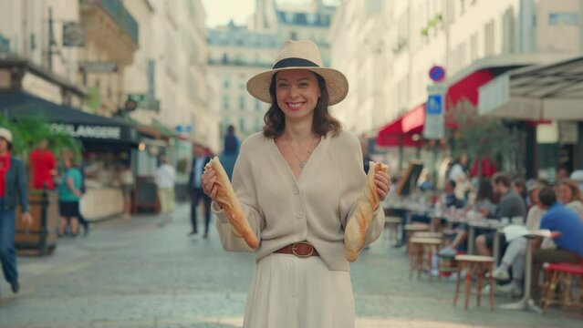 Joyful Woman Holding Baguettes on a Busy Paris Street