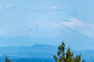 An airplane flying in front of Mount Saint Helens as viewed from Portland Oregon.