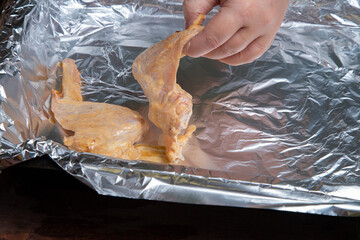 woman's hands lay out marinated chicken wings on foil for baking