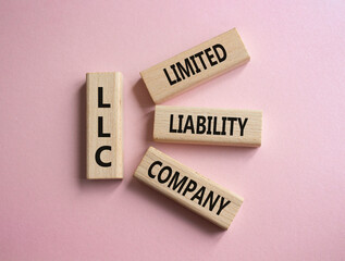 LLC - Limited liability company. Wooden cubes with word LLC. Beautiful pink background. Business...