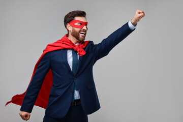 Happy businessman wearing red superhero cape and mask on beige background