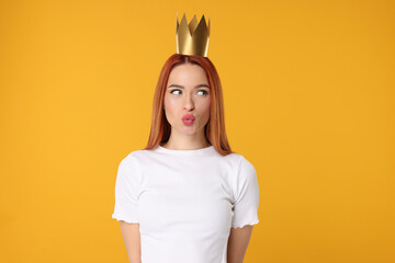Beautiful young woman with princess crown on orange background