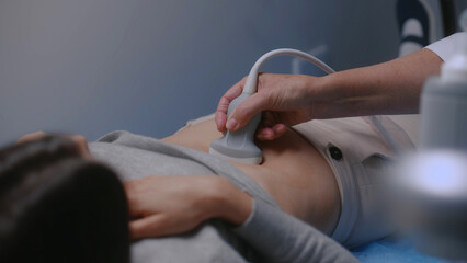 Caucasian woman undergoes ultrasound diagnostics of abdominal organs in modern clinic or hospital....