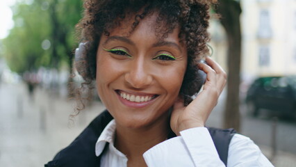 Woman wearing headphones dancing along on city street closeup. Girl in headset