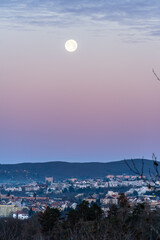 Brno, Czech Republic - Shining full moon in the evening blue sky above the skyline of city buildings. © Jan