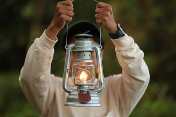 A girl was walking in the forest with a kerosene lantern in his hand.