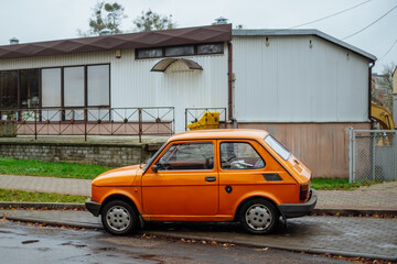 maluch or small fiat 126 in orange parked on the street