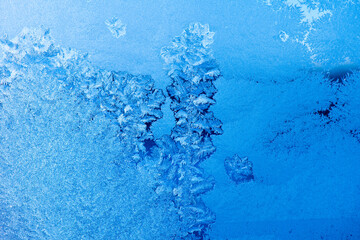 Frost patterns on a window in winter day (blue background)