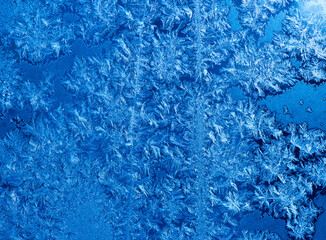 Frost patterns on a window in winter day (blue background)