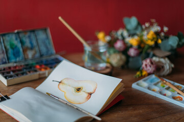 Artist's desktop with watercolors, palette, sketchbook