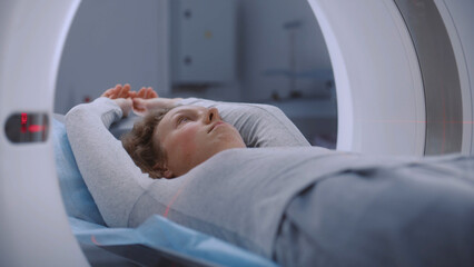 Close up portrait shot of woman lying on CT or PET or MRI scan bed and moving inside machine....