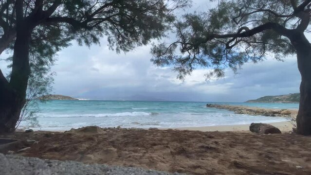 A beach with a rainbow and a stormy sky. blue ocean