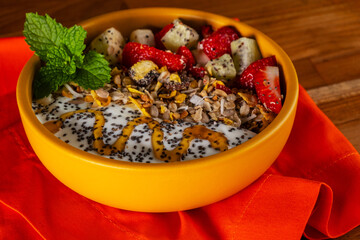 bowl with natural yogurt, granola, fruit, chia and honey
