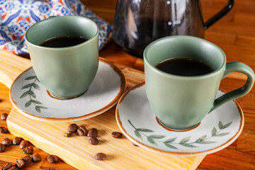 two cups of coffee and strainer used in the background