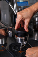 woman's hands pressing roasted and ground coffee to use in coffee maker