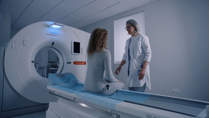 Professional radiologist lays female patient in MRI or CT or PET scan machine. Doctor conducts check up procedure in clinic with advanced medical technologies. High-tech modern medical equipment.
