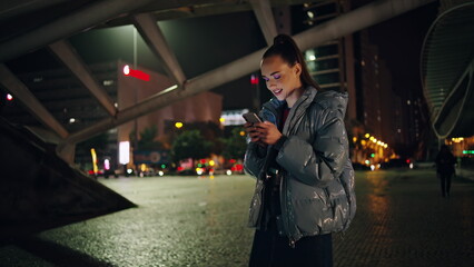 Girl teenager using smartphone at night city close up. Woman chatting at evening
