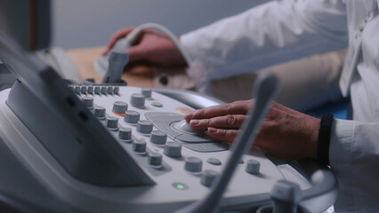 Doctor uses sonography machine with monitor. Medical specialist conducts stomach ultrasound...