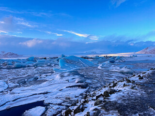 Fototapeta premium Icebergs swimming at the famous glacier lagoon around Vatnajokull National Park during winter around sunset time 