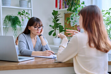 Middle-aged female psychologist, counselor working with young woman patient