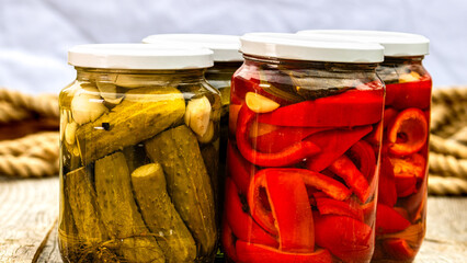 Glass jars with pickled red bell peppers and pickled cucumbers (pickles) isolated. Jars with...