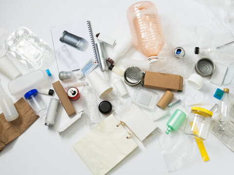 Recyclable plastic, metal and paper waste item over white surface.