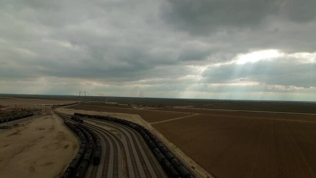 Aerial Forward Shot Of Freight Trains In Shunting Yard Under Cloudy Sky - Bakersfield, California