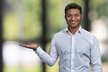 Successful young businessman showing empty space on blurred background. Man showing copy space on...