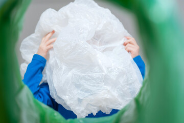 Low angle view child hand putting plastic wrap in a trash bin, recycling and waste sorting concept. Sustainability and environmentally conscious.