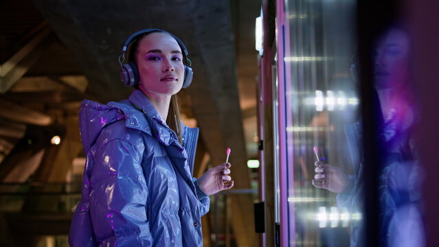 Girl touching snack automat making choice standing in night city subway close up