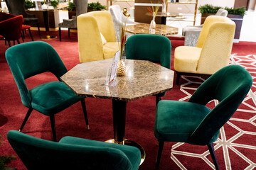 Elegant armchairs and table in a modern hotel lobby with luxurious decor.