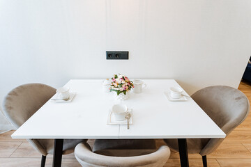 White marble dining table with pink rose bouquet and three cushioned chairs