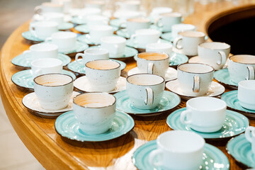 White and blue coffee cups on a round wooden table. Isolated on a white background.