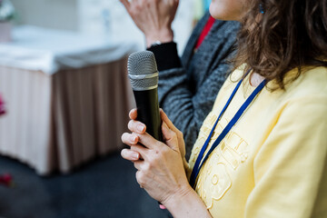 A woman holding a microphone in her hand while giving a speech at a conference
