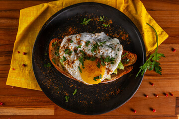 Sandwich with a slice of Italian bread, avocado and fried egg with runny yolk