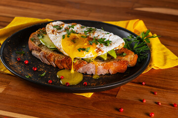Sandwich with a slice of Italian bread, avocado and fried egg with runny yolk