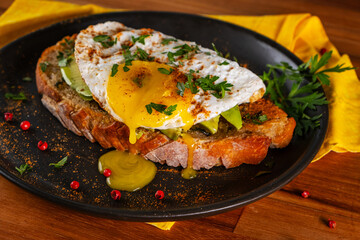 Sandwich with a slice of Italian bread, avocado and fried egg with runny yolk