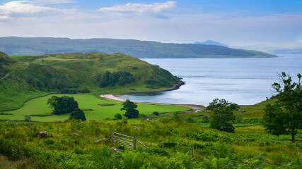 Green countryside surrounding Bay of Pledges beach and ocean, Scotland in summer.