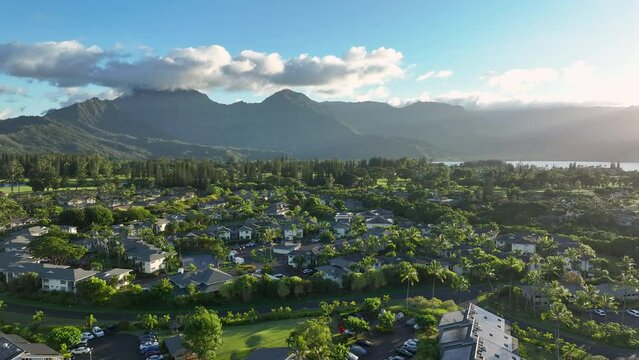 Aerial Kauai Princeville resorts ocean mountain sunset 1. Expensive luxury homes, resort, condominium and golf club near coast. Recreation and tourism. Green landscape. Economy tourism based.