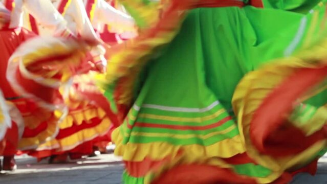 close up group of mexican female dancers energetically waving their colorful mexican folk dresses, mariachi music, Mexico heritage