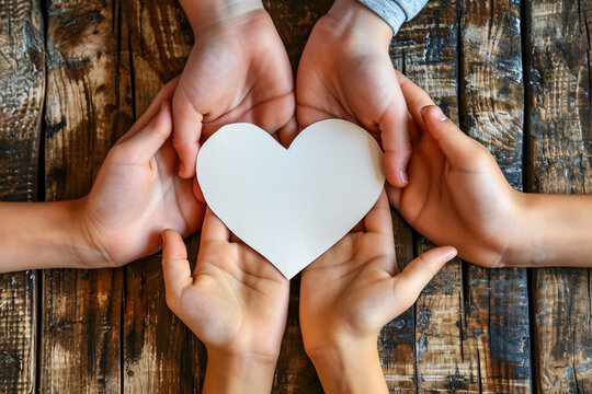 Multiple hands holding a heart-shaped paper cutout symbolizing family unity and support for various social causes.