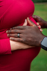 Multinational couple expecting a baby. Pregnant woman holds her hands on a belly with husband.